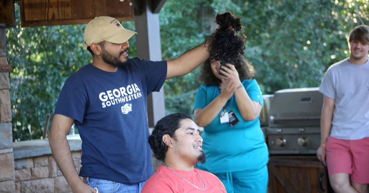 student shaves hair outside